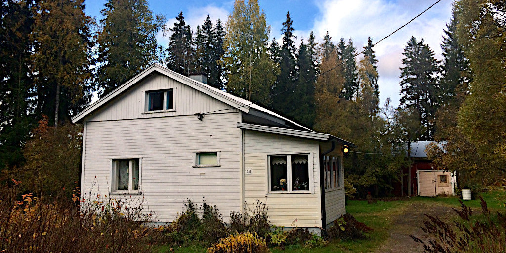 Valkoinen talo ja pihapiiri.